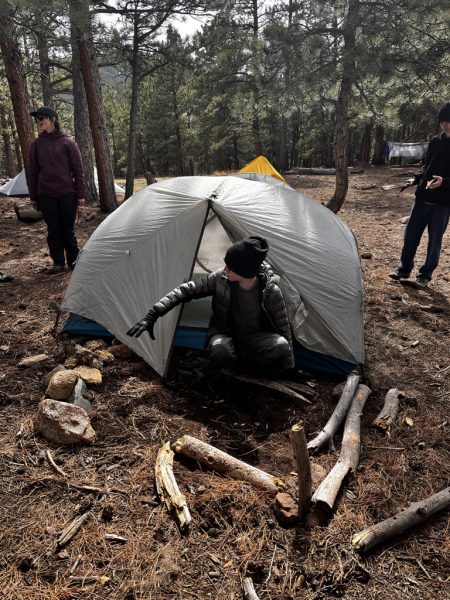 A student in their tent on their overnight camping trip. 