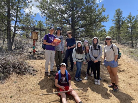 DCS students pose in front of a trail sign at Ben Delatour