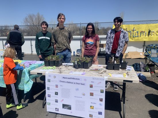 Four Changemakers pose with their Lafayette Earth Day Fair table, where they are giving away native plants to help support pollinators. 