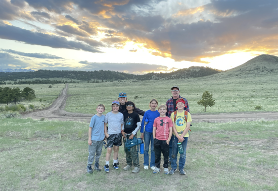 Littleton Academy students pose in front of a beautiful sunset at Mission:Wolf