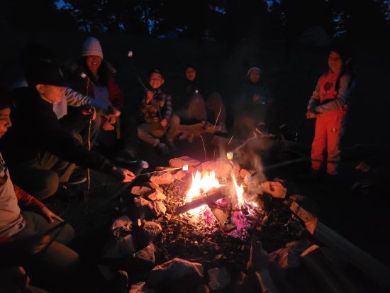 Students and parents roast smores by the fire at Mission: Wolf