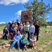 A group of Casa de la Esperanza students, parents, and instructors pose by the Mission: Wolf sign