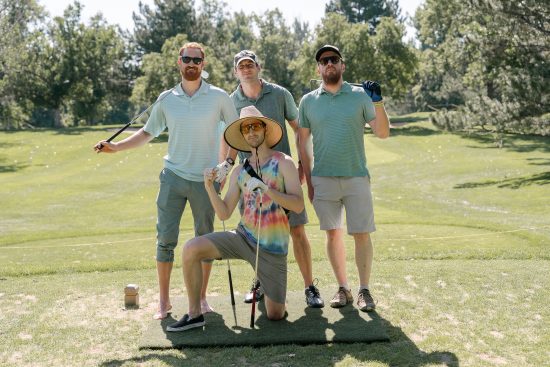 A team of 4 poses on the green at the Harvard Gulch 2023 Golf Tournament