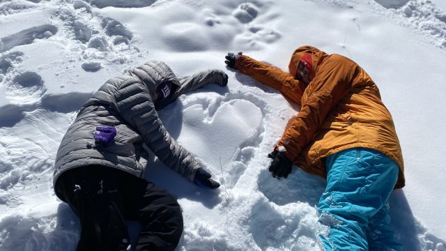 two people laying in the snow