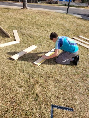 An Angevine Middle School student measures lumber to help build a Gaga Ball pit at their school