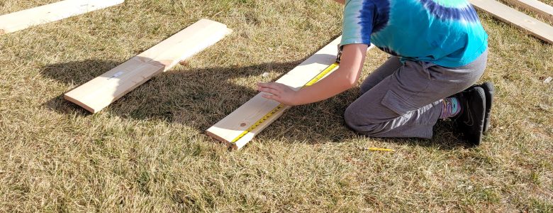 An Angevine Middle School student measures lumber to help build a Gaga Ball pit at their school