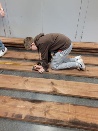 An Angevine Middle School student measures lumber to help build a Gaga Ball pit at their school