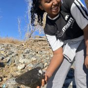 An AXL Academy 8th grade student picks up a rock while exploring Pelican Ponds Open Space