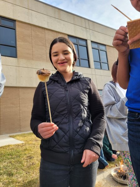 A Centaurus High School student roasts a marshmallow on a fire they built with their class