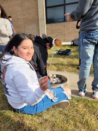 A Centaurus High School student roasts a marshmallow on a fire they built with their class