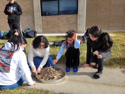 A Centaurus High School student roasts a marshmallow on a fire they built with their class