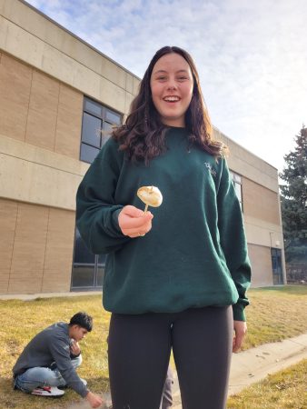 A Centaurus High School student roasts a marshmallow on a fire they built with their class