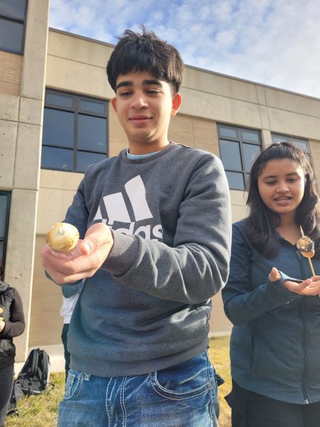 A Centaurus High School student roasts a marshmallow on a fire they built with their class