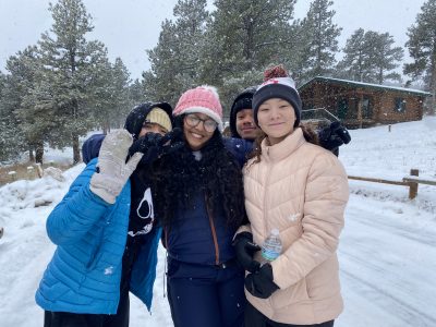 AXL Academy 8th grade students huddle together happily in the snow