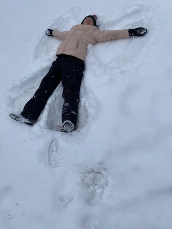 An AXL Academy 8th grader makes a snow angel