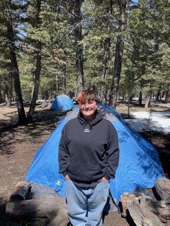 an NVHS student poses in front of a tent