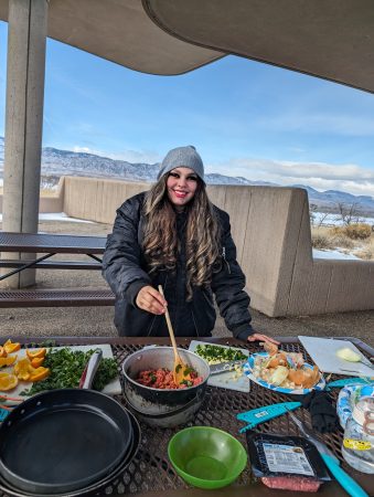 A RiseUp student cooks on a camp stove