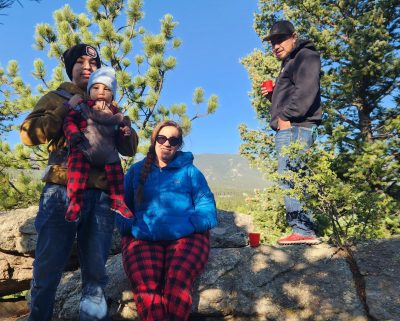 Family members (including a baby) pose for a photo in nature during the Casa intergenerational outdoor trip.