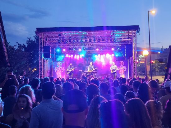The audience watches the band play on stage under the lights at Beats on the Creek 2025.