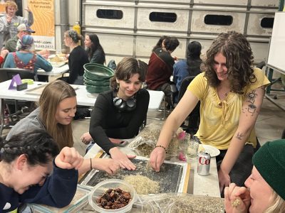 Cottonwood community members are gathered around tables preparing native seeds for a local restoration project.