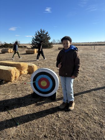 An AXL 7th grader stands by the target after he hit the bullseye with arrows while learning archery.