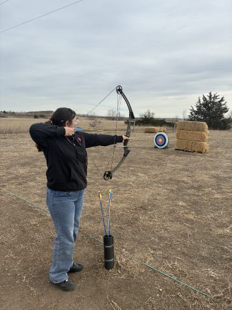 An AXL student tries to hit the target using a bow and arrow .