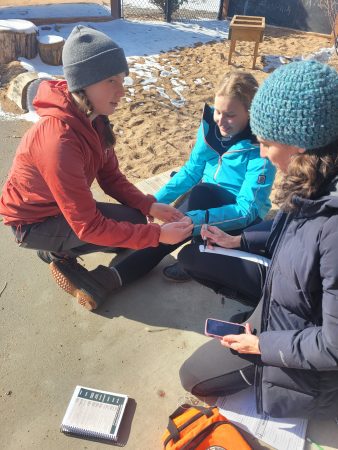 Changemaker students and a Cottonwood Instructor practice their wilderness first aid skills in a scenario outdoors.