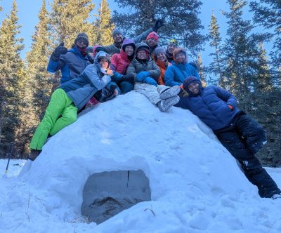 Cottonwood staff members pose on top of the quinzee they built during winter training.