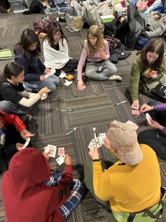 AXL 7th graders play cards in a circle during their CAP overnight.