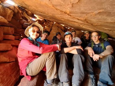 Peak to Peak students pose under a huge rock during their canyon backpacking adventure.