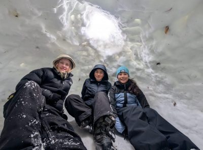 Three students lie inside their quinzee in preparation for sleeping inside it.