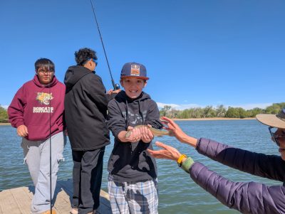 An Angevine smiles with joy as he holds up the fish he caught while at Waneka Lake.
