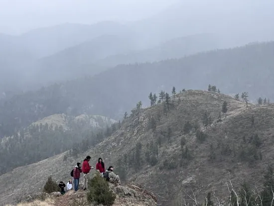 Several students stand looking at the view of the mountains shrouded in fog and snow, filling them with a sense of wonder.