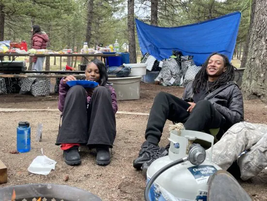 Two students sit around the campfire during the CHSC CAP overnight camping trip.
