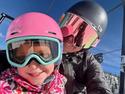 Cottonwood Board member, Alyssa, poses on a chairlift while skiing with one of her children.