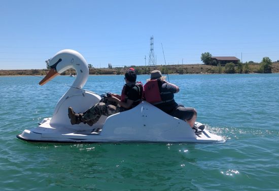 Students in the Casa teen outdoor leadership program fish off the side of a paddle boat.