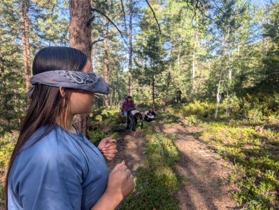 One Casa teen is blindfolded at the campsite while other students try to sneak up on her.