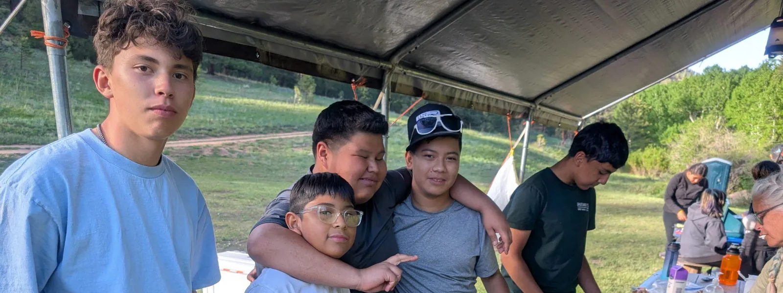 Students in the Casa teen outdoor leadership program cook a meal together on a camp stove.