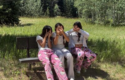 Three LYC girls hide their faces with silly hand gestures as they sit on a bench at Golden Gate Canyon State Park.