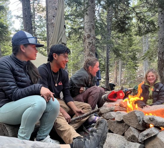 Students hang out around the campfire during their summer Changemakers adventure.