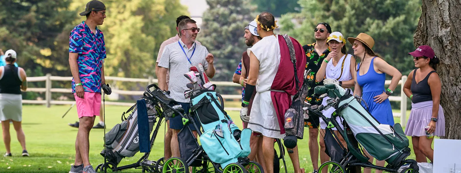 Golfers gather (including those in costumes) with their gear during the 2026 Golf Invitational at Harvard Gulch.