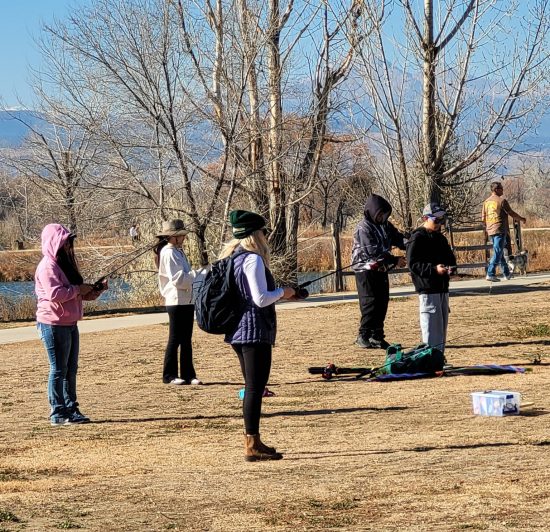 A group of Lafayette youth learn how to fish by practicing on the grass.