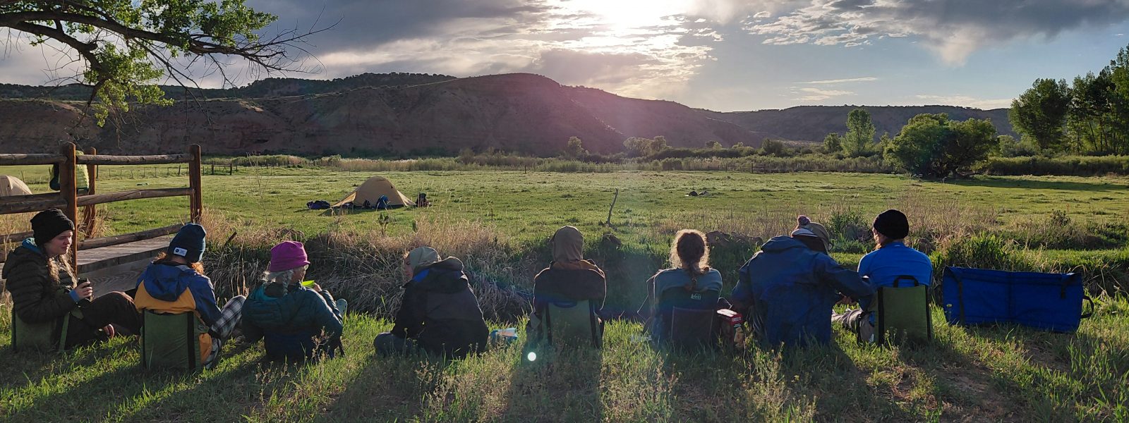 Changemaker students sit outside enjoying a sunset during a trip on their year of outdoor leadership and environmental stewardship.