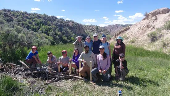 Changemakers students pose near a beaver dam analog, which they created during their year-long program focused on environmental stewardship.