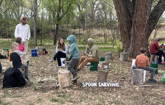 Lafayette youth join community members in a spoon carving area at the Ancestral Skills Gathering in April 2026.
