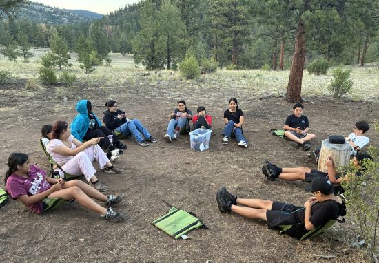Horizons at Colorado Academy students sit in a circle at their campsite while taking a break from teamwork-focused activities.