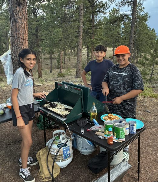 Three students cook dinner over the camp stove at Camp Serenity.
