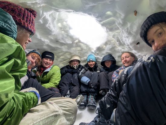 Changemaker participants huddle in the quinzee they created on their winter overnight trip.