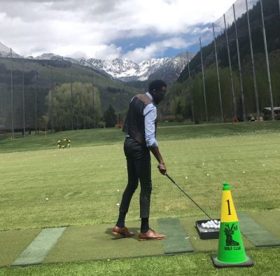 CI Board member D'Andre stand on a driving range with a view of snow covered mountains.