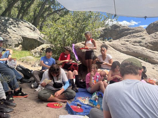 The AXL Academy CAP class enjoys lunch under the shade of a tarp they rigged up themselves.